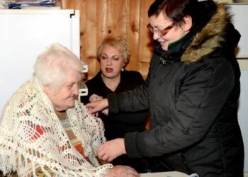 Anykštietę Oną Šaltenienę skara apgobė Trečio amžiaus universiteto direktorė Nijolė Radušienė, viduryje – Anykščių socialinių paslaugų centro darbuotoja Vilma Kazlovienė ką tik įteikusi kalėdinę dovanėlę.