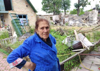Senolė Nina prie sugriautų pastatų.